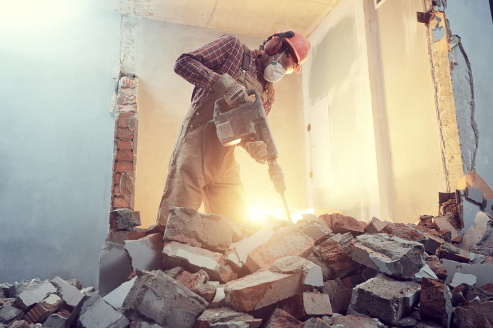 Worker breaking through a brick wall with a demolition hammer