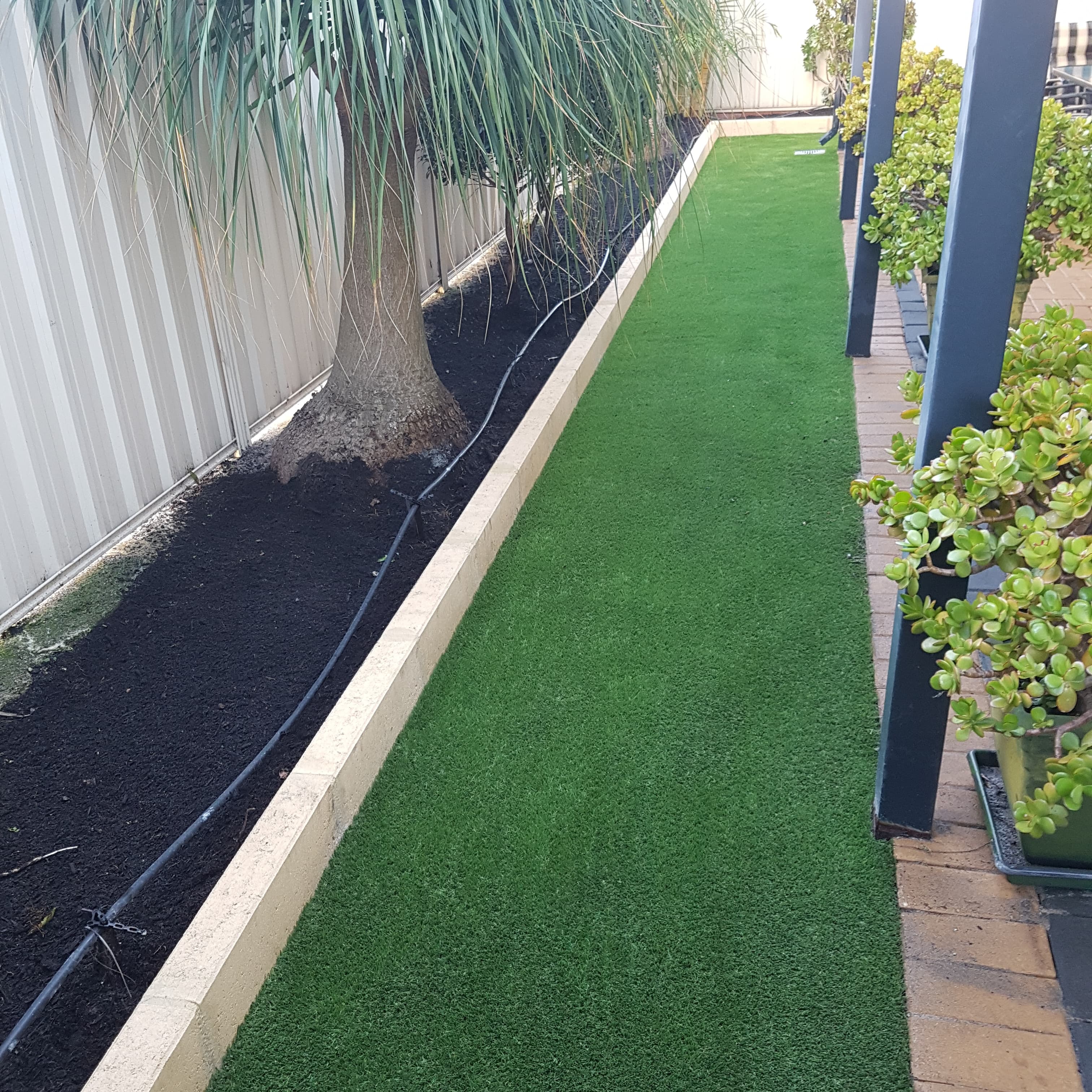 Artificial turf lawn framed by paving, Perth backyard